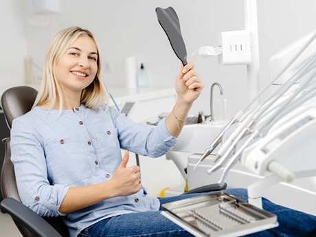 Happy cosmetic dentistry patient holding hand mirror