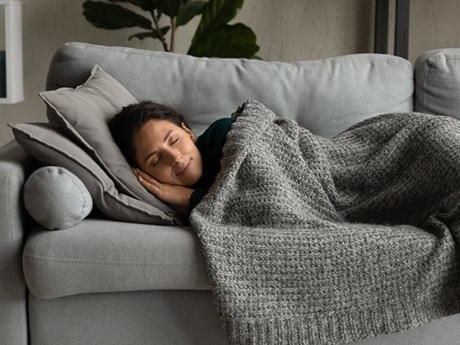 Woman sleeping on her couch with a cozy blanket