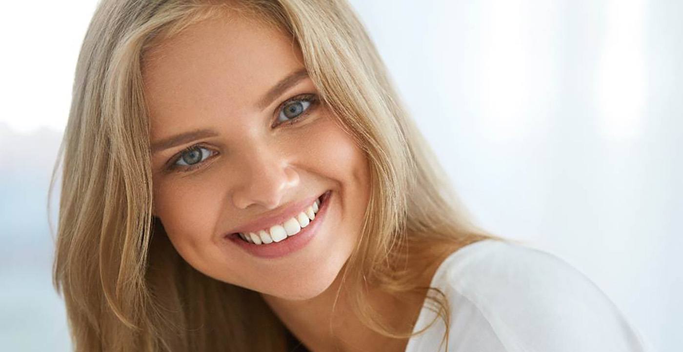 A smiling blonde woman looking directly at the camera