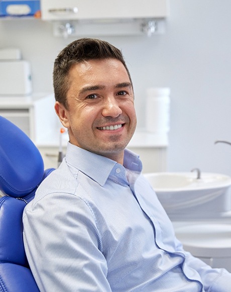 Male patient sitting in dental chair and smiling