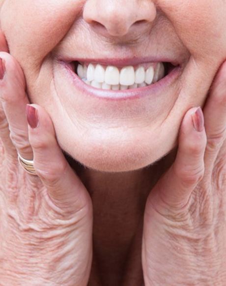 a woman smiling after caring for her dentures