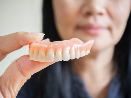 a person holding a pair of dentures  