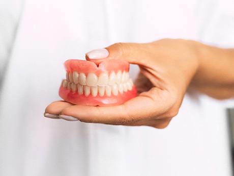 Close-up of hand holding dentures in Huntsville, OH