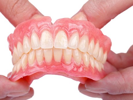 Close-up of dentures in Huntsville, OH held in two hands
