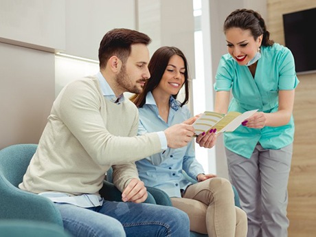 dental team member showing a pamphlet to two patients