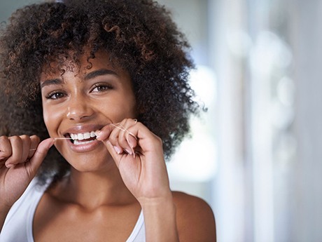 woman smiling while flossing her teeth