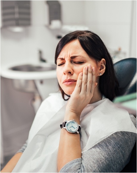 Woman holding cheek in pain before emergency dentistry treatment