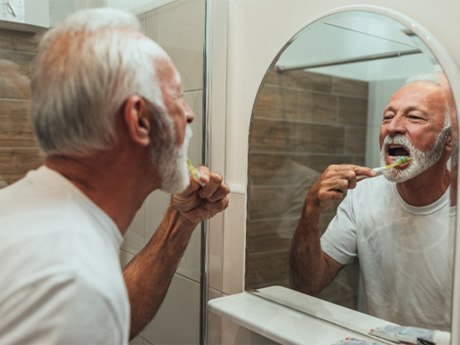 mature man brushing teeth for cost of dental implants in Huntsville