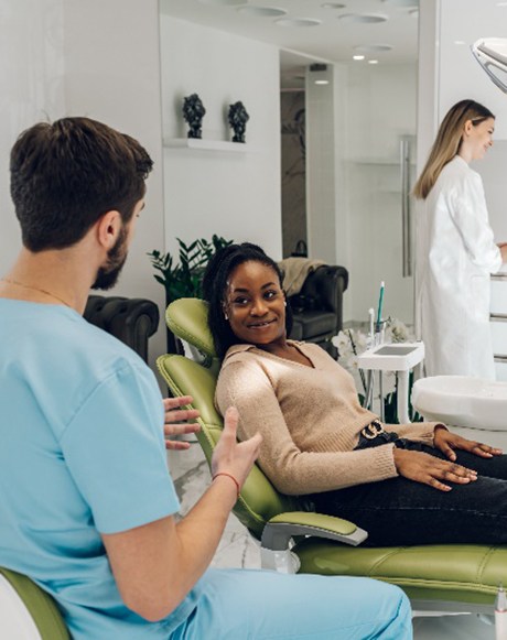 Female patient smiling at dentist while sitting in treatment chair