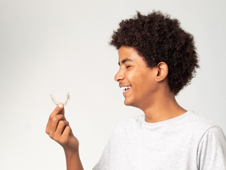 Profile view of young man holding Invisalign with markings on tray