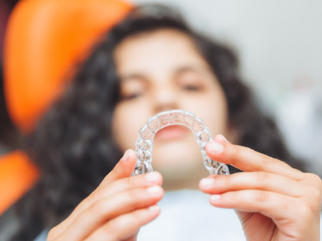 Young woman blurry in background holding Invisalign
