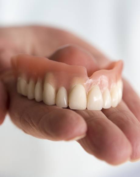 Hand holding a full denture