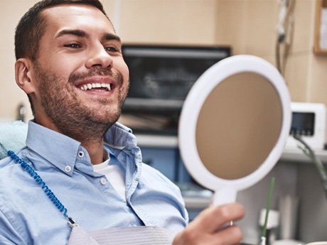 a man checking his teeth after his dental appointment  