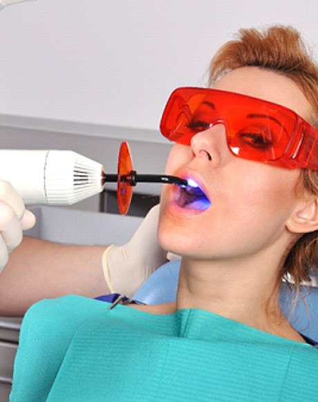 A dentist performing a filling treatment on a woman