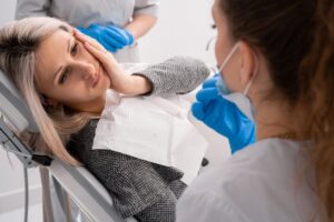 Woman holding mouth in pain in the dentist's chair. 
